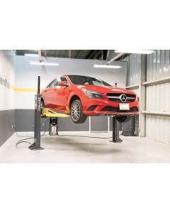 Red Mercedes sedan raised by MaxJax M7K two-post lift in a BendPak service bay, demonstrating balanced mid-rise positioning.