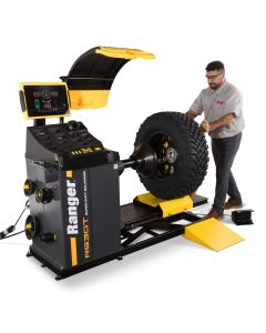 Technician loading a large off-road tire onto the Ranger RB30T 5140179 heavy-duty truck wheel balancer with safety hood raised.