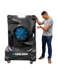 Man standing next to the Cool Boss CB-16 portable evaporative air cooler — large indoor/outdoor space-saving shop fan with black body, blue fan blades, and LED light.