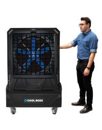 Man standing beside the Cool Boss CB-26 portable indoor/outdoor evaporative air cooler — large space-saving shop-fan with blue blades and rugged black housing.
