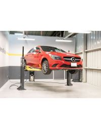 Red Mercedes sedan raised by MaxJax M7K two-post lift in a BendPak service bay, demonstrating balanced mid-rise positioning.