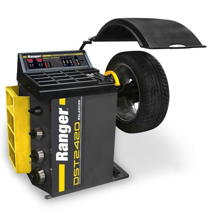 Ranger DST2420 digital wheel balancer with LED display, open wheel guard, and mounted tire. Compact, black-and-yellow cabinet design with side cone storage and top tray compartments.